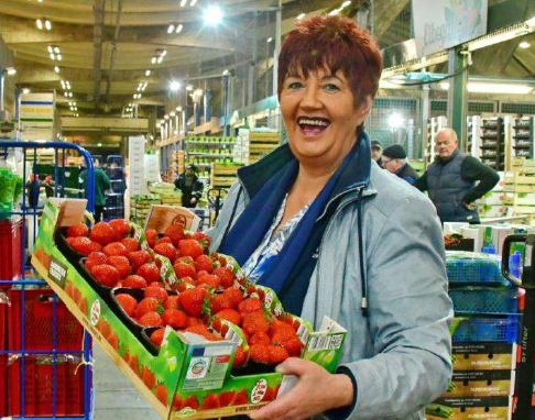 Eine Mitarbeiterin eines Großhändlers mit einer Stiege Erdbeeren